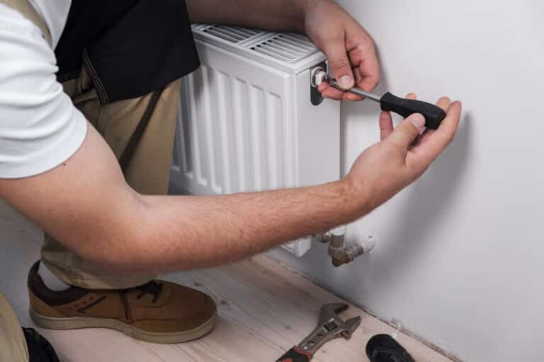 Plumber installing new steel hot water central heating radiator